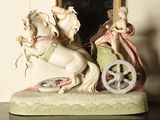 a figurine of a horse pulling a carriage with a woman on it