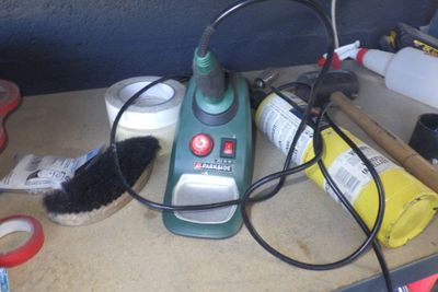 un aspirateur vert et noir posé sur un plan de travail, muni d'une brosse