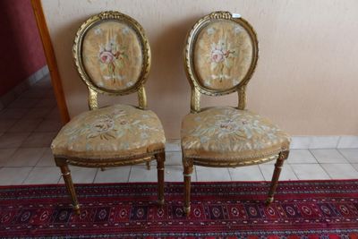 une paire de chaises anciennes aux assises rembourrées de motifs floraux, posées sur un tapis