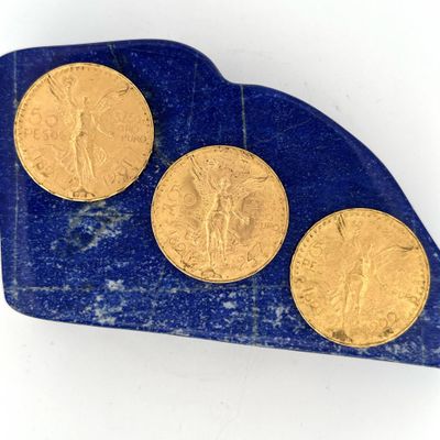 trois pièces d'or posées sur un morceau de marbre bleu