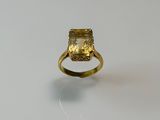 a close up of a ring on a white surface with a yellow stone
