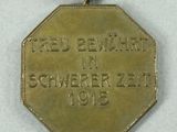 a gold medal with a red and white ribbon around it