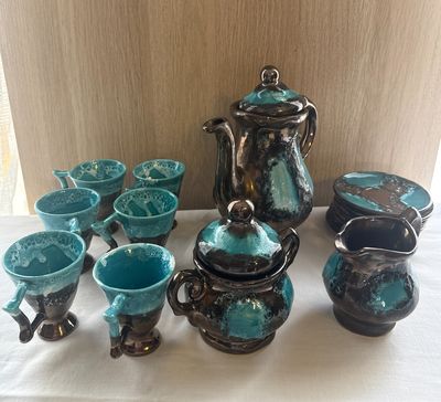 many pieces of pottery on a table with a white table cloth