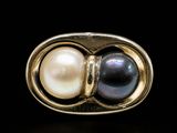 a close up of a ring with two pearls inside of it