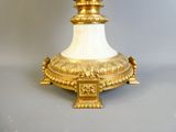 un vase doré et blanc posé sur un socle, sur une surface grise