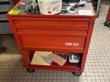 un établi rouge sur lequel se trouve un seau rempli d'outils