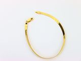 gros plan d'un bracelet en or sur une surface blanche