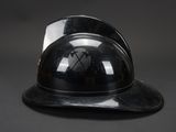black hard hat sitting on top of a black table next to a black wall