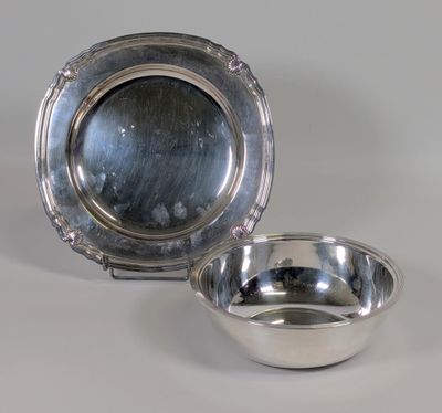 une assiette et un bol en argent sur une surface blanche avec un fond gris