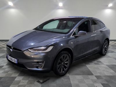 un SUV Tesla gris garé dans un garage au sol à damier