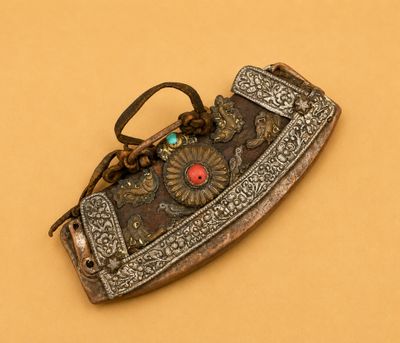 une vieille broche argentée et rouge sur fond marron