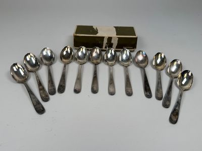 six cuillères en argent et une boîte de cuillères en argent posées sur une table