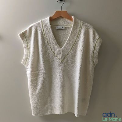 Le pull blanc est suspendu à un cintre accroché au mur.