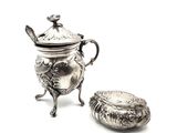 a silver teapot with a lid sitting next to a small bowl