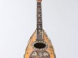 an old wooden instrument hanging from a string on a white wall
