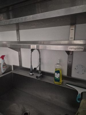 a sink in a kitchen with a metal shelf above it