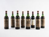 six bottles of wine lined up in a row on a white surface