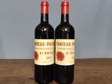 two bottles of red wine sitting on top of a wooden table