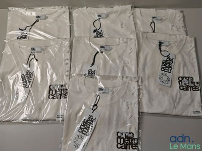 Quatre t-shirts blancs ornés de logos noirs et blancs sont posés sur une table