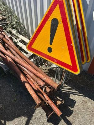 yellow and red warning sign sitting on top of a pile of rusted metal