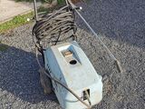 a lawn mower on the ground next to a car