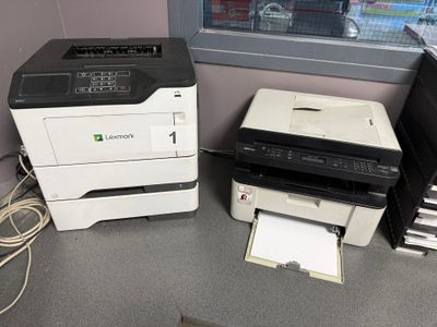 deux imprimantes posées sur un bureau près d'une fenêtre