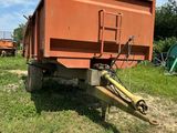 un camion-benne orange garé dans un champ à côté d'un tracteur vert