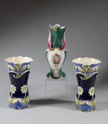 trois vases sont posés sur un socle, sur une surface grise