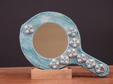 un miroir bleu posé sur un socle en bois, lui-même posé sur une table