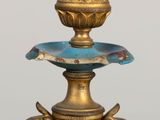 a gold candle holder with a bird on top of it