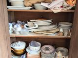 a cupboard full of plates and bowls in a kitchen