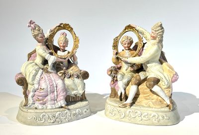 deux figurines représentant un couple assis sur une chaise avec un chien