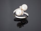 une bague en perles blanches et diamants sur une surface noire