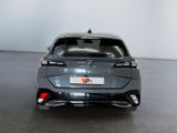 the rear end of a grey car in a room with a white wall
