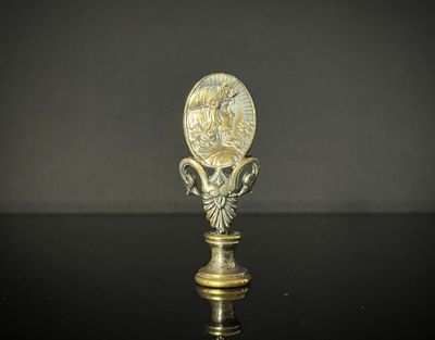 une cuillère ancienne en laiton, sur laquelle est représenté un visage, posée sur une surface noire
