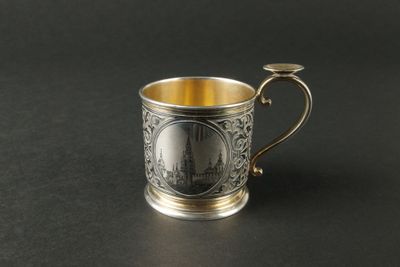 une coupe en argent munie d'une anse, posée sur une surface noire