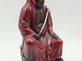 an image of a statue of a man sitting on a rock