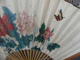 a fan with a painting of flowers and a butterfly on it