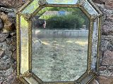 une image représentant un miroir accroché à un mur de pierre dans un jardin