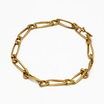 gros plan d'un bracelet en chaîne en or sur fond blanc