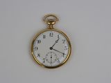 une montre de poche en or avec un cadran blanc sur une surface blanche