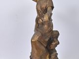 bronze statue of a woman sitting on a rock with her hands on her head