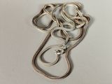 a close up of a silver necklace on a white surface