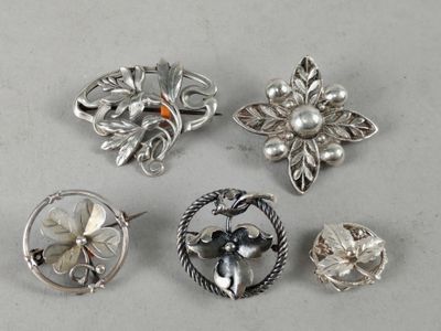 six silver brooches with flowers and leaves on them on a white surface