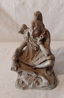 une petite statue représentant une femme assise sur un rocher