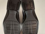 black leather slippers on a white surface with a white background