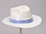 white and blue hat on a gold stand against a gray background