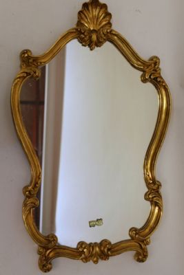 a gold mirror hanging on the wall next to a mirror