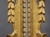 a gold colored clock with a thermometer on it