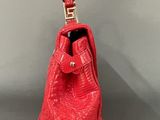 red leather handbag on grey background with gold hardware